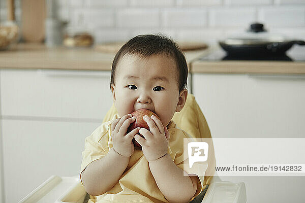 Cute girl eating apple sitting at home