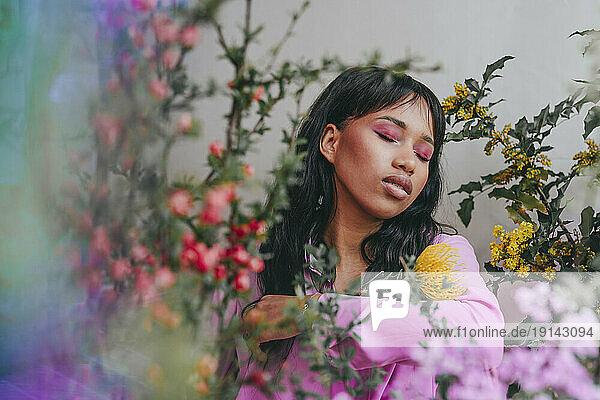 Young woman with eyes closed amidts different flowers