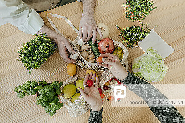 Couple unpacking fruits and vegetables from mesh bag