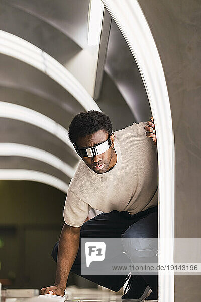 Futuristic man with cyber glasses crouching in metro tunnel