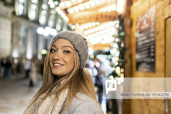 Happy young woman wearing knit hat at Christmas market