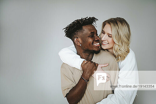 Smiling young couple embracing against gray background
