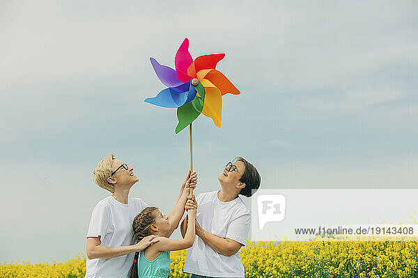 Happy lesbian mothers and daughter holding pinwheel toy at field
