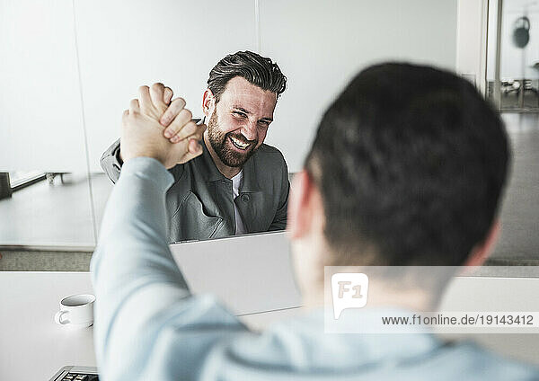 Happy businessman giving high-five to colleague at office