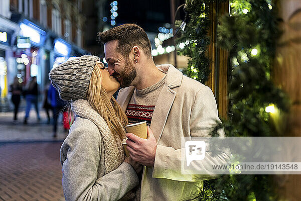 Happy couple kissing and embracing each other at Christmas market