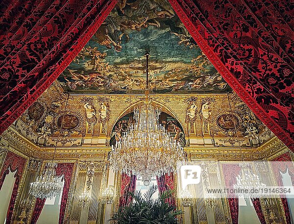 Schön dekorierte Napoleon Appartements im Louvre Palast. Zimmer der königlichen Familie mit kardinalroten Vorhängen  goldenen  verzierten Wänden  Gemälden und von der Decke hängenden Kristalllüstern
