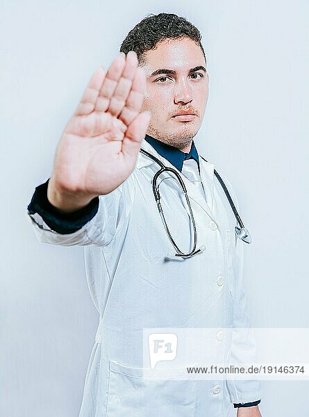 Gutaussehender Arzt  der eine Stoppgeste macht  isoliert  Junger Arzt  der mit der Handfläche eine Stoppgeste macht