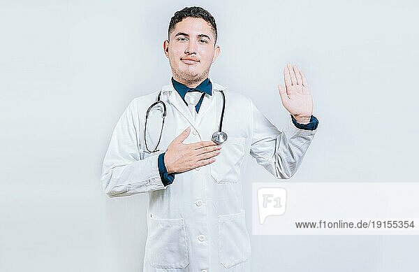 Junger Arzt hebt die Hand und schwört isoliert. gut aussehend Arzt macht Eid und Versprechen isoliert