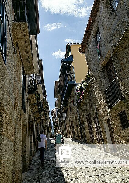 Zwei Personen gehen an Häusern in einer steilen  engen Straße in der mittelalterlichen Stadt Ribadavia  Provinz Ourense  Galicien  Spanien  vorbei  Europa