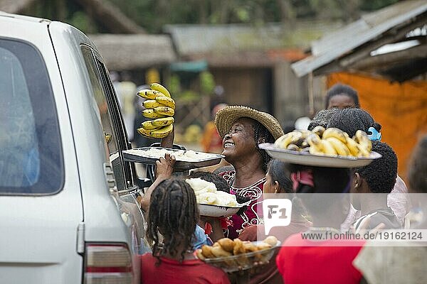 Einheimische madagassische Frauen verkaufen Bananen und Lebensmittel an Passanten  die in einem Fahrzeug in einem ländlichen Dorf in Madagaskar  Südostafrika  unterwegs sind