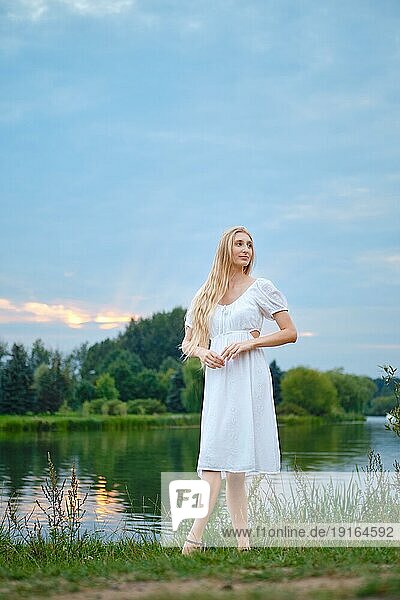 Verträumte junge Frau am Abend am Fluss