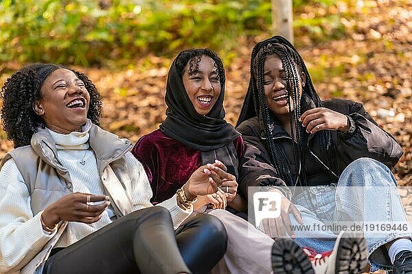 Multikulturelle Gruppe junger Frauen  die in einem Park sitzen und Spaß haben