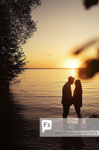 Couple embracing each other in front of sea at sunset