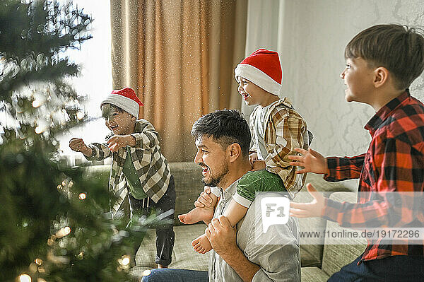 Father and sons having fun on sofa near Christmas tree