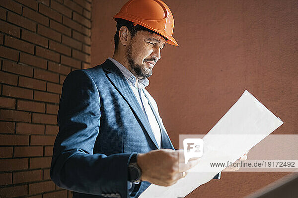 Engineer wearing hardhat reading and document at construction site