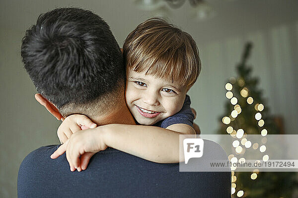 Father embracing smiling son at home