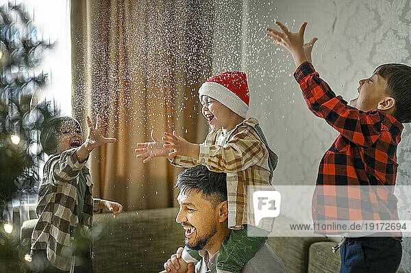 Father and sons playing with fake snow at home