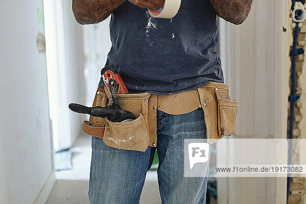 Construction worker wearing tool belt standing at site