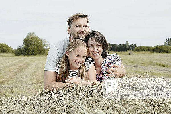 Happy family leaning on hay in field