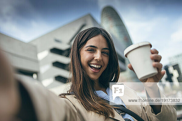 Happy young woman taking selfie with coffee cup