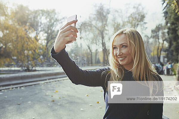 Smiling woman taking selfie through smart phone