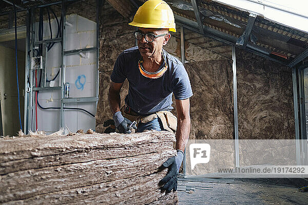 Mature construction worker with stack of insulations at site
