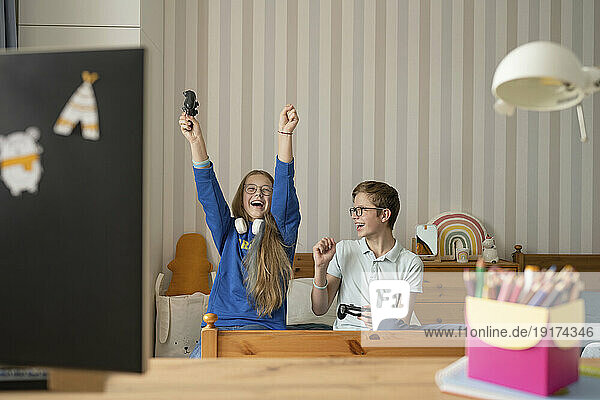 Cheerful girl celebrates winning video game with friend at home