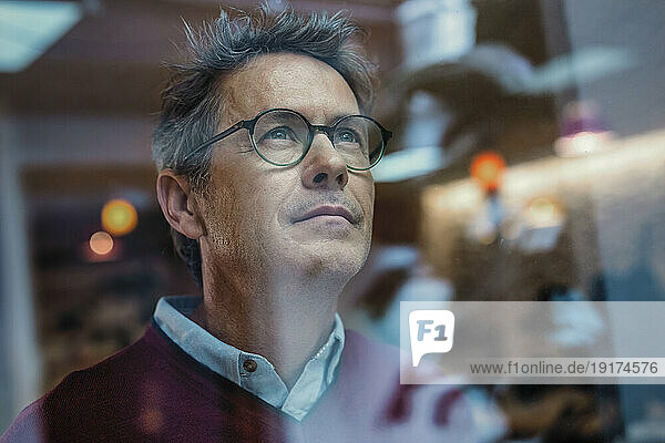 Businessman wearing eyeglasses seen through glass in office