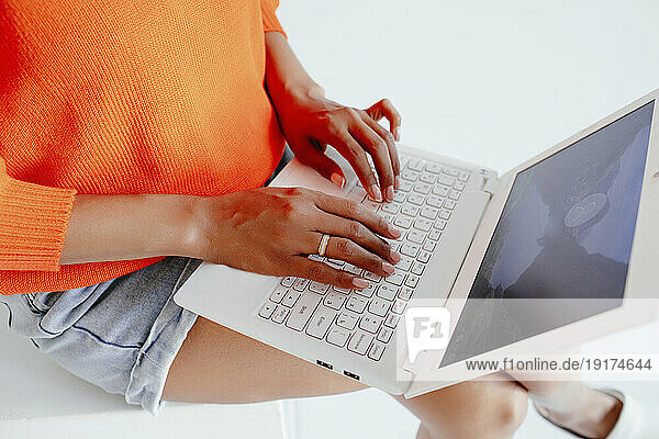 Young woman online shopping through laptop in studio