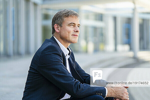Serene businessman sitting in front of modern office building