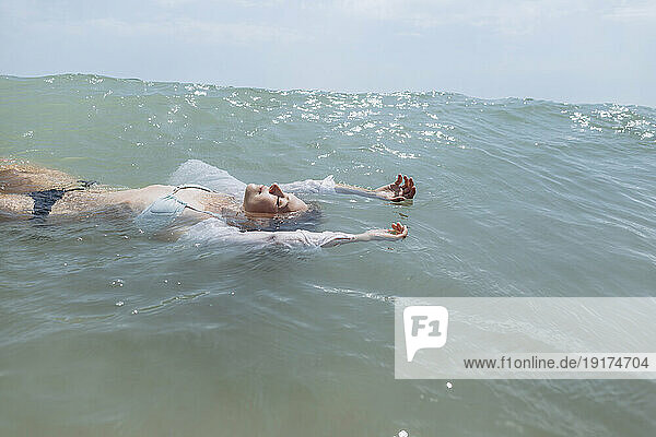 Woman wearing bikini floating on water in sea