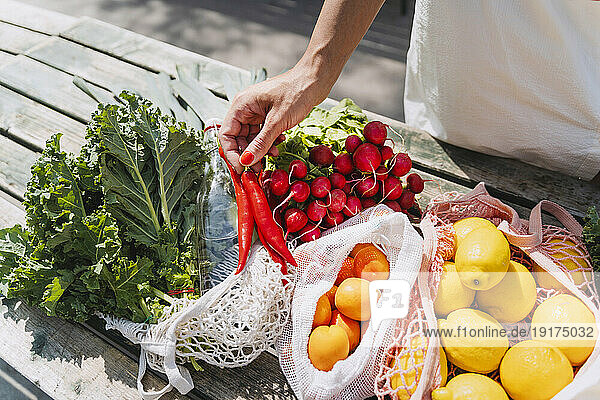 Woman holding red chilies and buying fresh vegetables in market