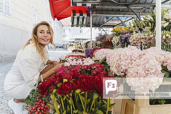 Smiling blond woman buying flowers in market