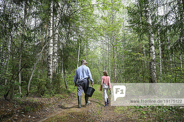 Senior man with his granddaughter walking in forest
