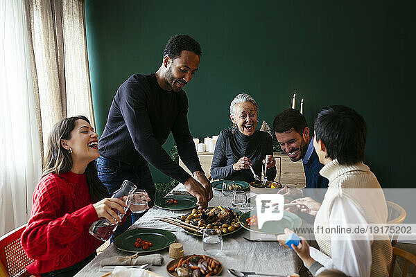 Multiracial family laughing and enjoying dinner at home
