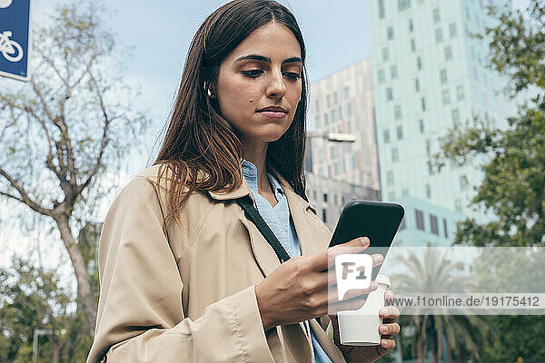 Young woman using smart phone in city
