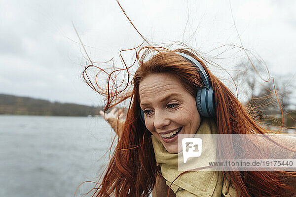 Happy redhead woman enjoying listening to music