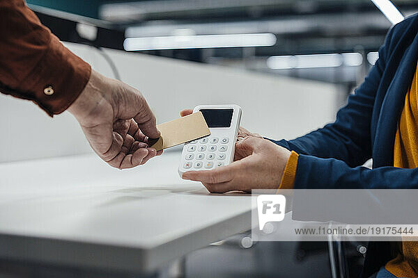Hand of businessman paying on POS system at office