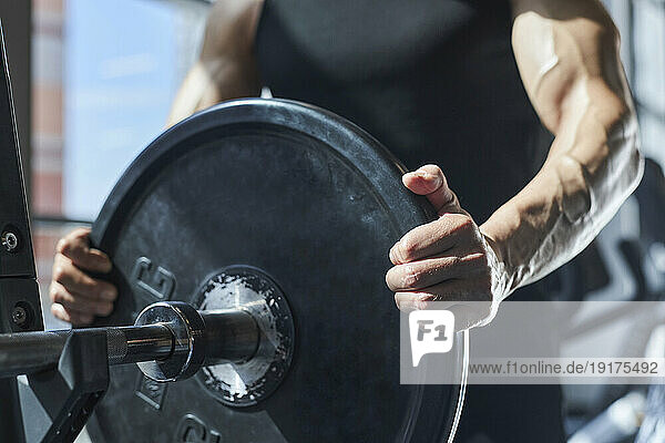 Mature man holding barbell in gym