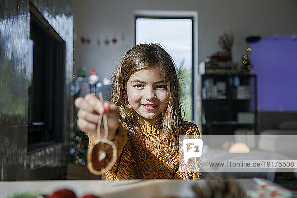 Happy girl holding dried lemon at home