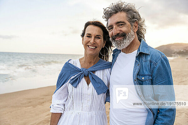 Smiling heterosexual couple standing at beach on weekend