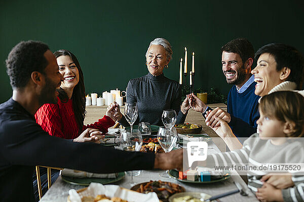 Happy family holding hands with each other at dining table