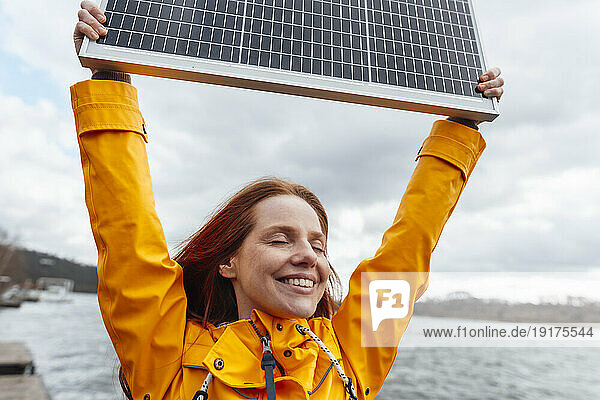 Smiling woman with eyes closed holding solar panel