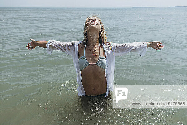 Happy woman with arms outstretched standing in sea