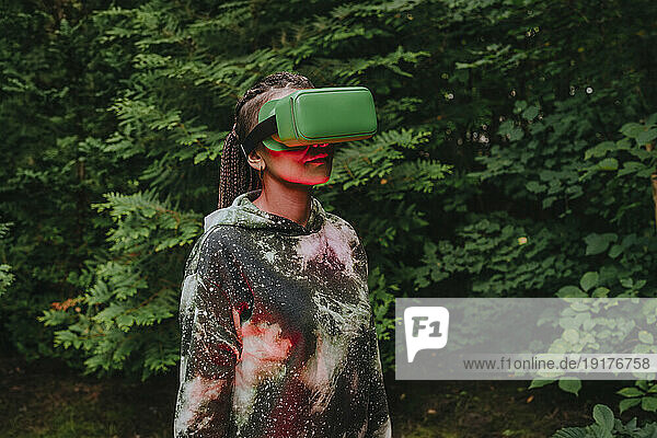 Woman wearing VR glasses with illuminated red light in forest