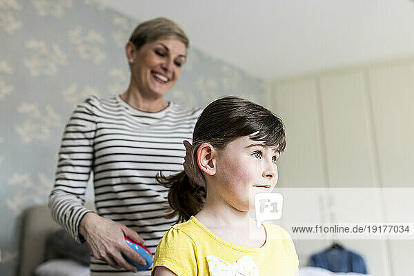 Mother tying daughter's hair at home