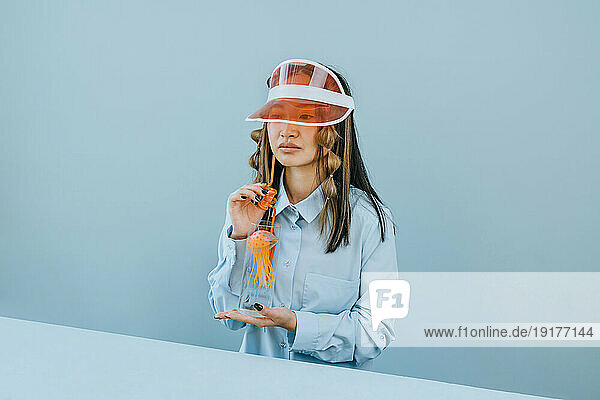 Young woman wearing sun visor and having water with jellyfish in studio