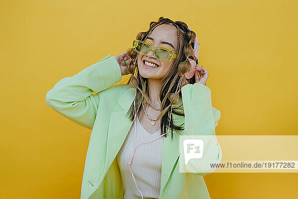Happy woman enjoying music through headphones in studio