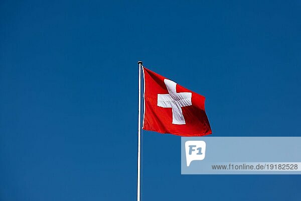 Schöne Schweizer Flagge gegen blauen klaren Himmel in einem sonnigen und windigen Tag in der Schweiz