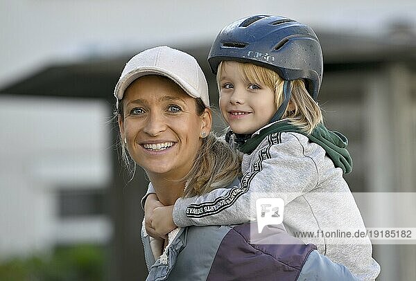 Mutter  Frau  blond  Basecap  lächelt  trägt Junge mit Helm  5 Jahre  blond  auf Schulter  Stuttgart  Baden-Württemberg  Deutschland  Europa